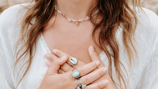 Close-up of a person wearing multiple rings and a necklace with a blurred background